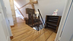 A room with wooden flooring, a staircase, and a white door.