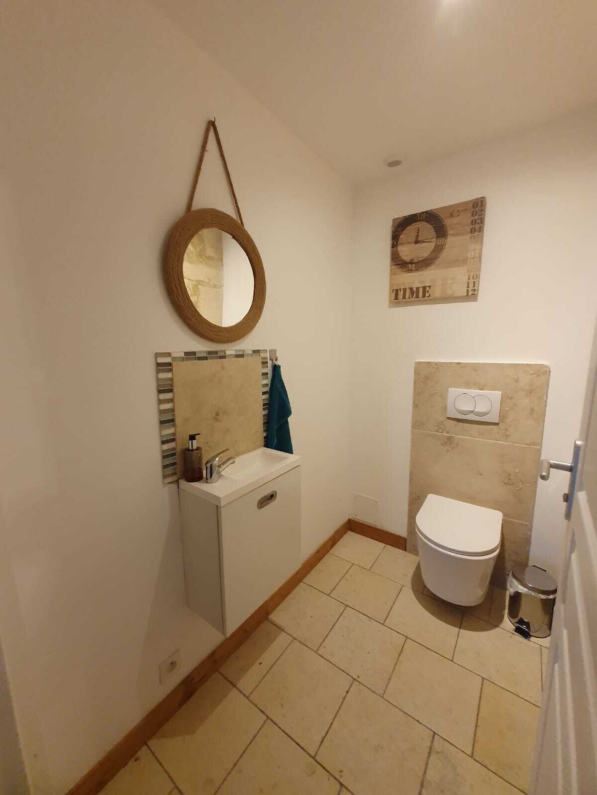A small bathroom with a toilet, sink, and mirror.