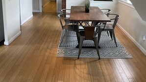 A dining area with a wooden table and chairs, a patterned rug, and a ceiling fan.
