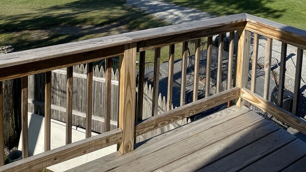 A wooden deck overlooking a golf course with a clear path leading to the tee area.