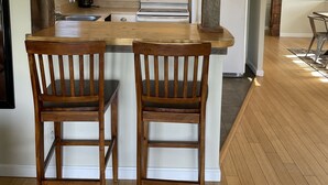 A kitchen with wooden chairs, a stove, and white cabinets.
