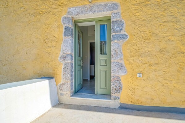 A doorway with a stone frame leading to a room with a green door. - Alexander House Apartment 2 (Leonidi)