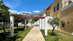 A courtyard with a stone pathway, white columns, and a building with a red-tiled roof.