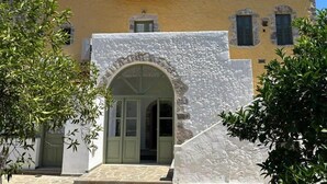 A building with a stone archway entrance, a yellow facade, and a small window.
