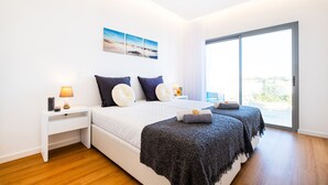 Een moderne slaapkamer met een groot bed, een nachtkastje en uitzicht door een schuifdeur.
