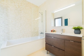 A modern bathroom with a glass-enclosed shower, a white bathtub, and a wooden vanity with a mirror above. - Townhouse Varadero (Albufeira)