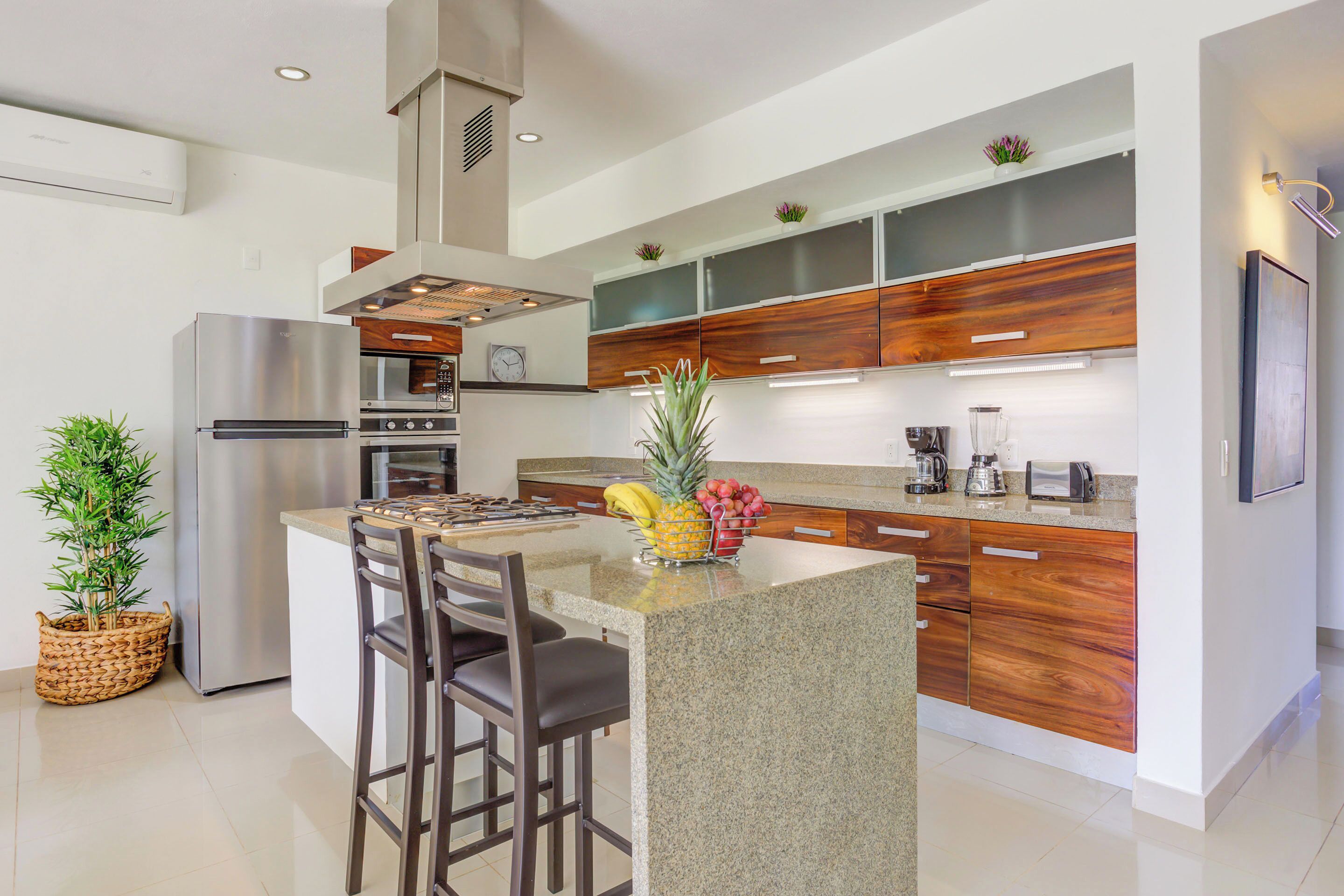 A modern kitchen with a central island, stainless steel appliances, and wooden cabinetry.