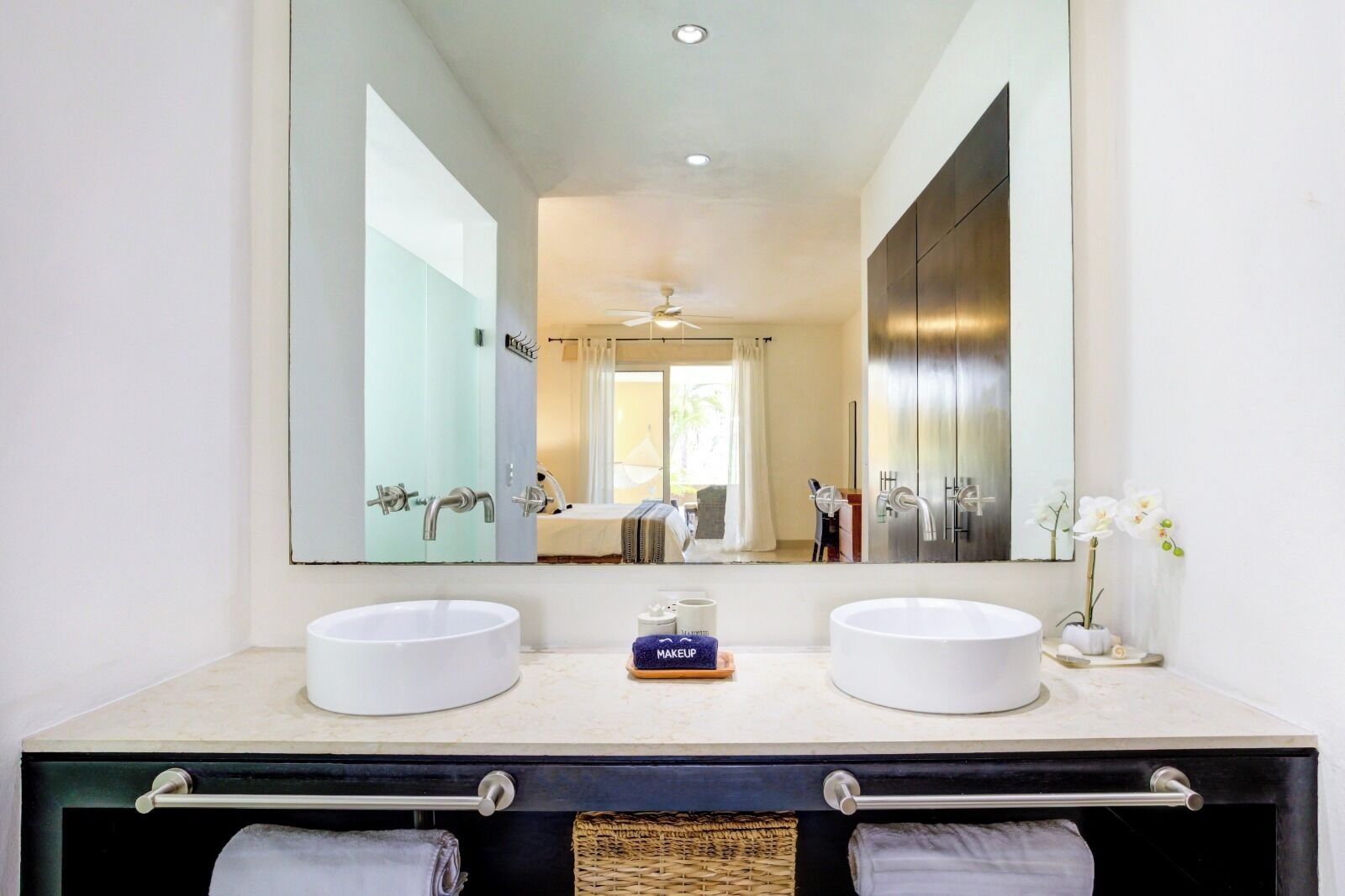 Un bagno moderno con due lavandini, uno specchio grande e un portasciugamani.