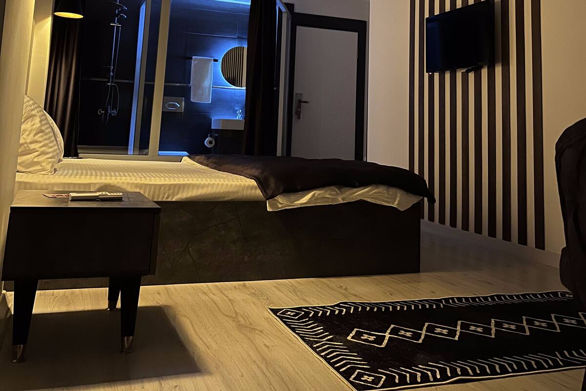 A modern bedroom with a bed, bedside table, and a TV mounted on the wall.