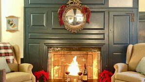 A living room with a fireplace, two armchairs, a coffee table, and a mirror above the fireplace.