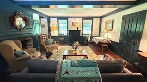 A cozy living room with a fireplace, a dining area, and a large window.