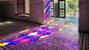 Un interior con intrincados trabajos en azulejos, un suelo estampado y un amplio ventanal arqueado con vidrieras de colores.