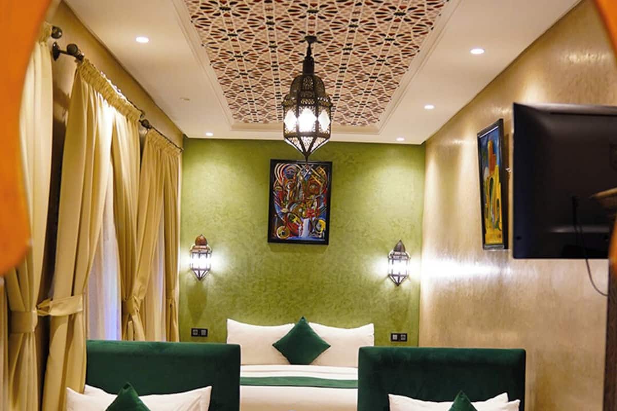 Habitación de hotel con dos camas, suelo estampado, techo decorativo y un cuadro en la pared.