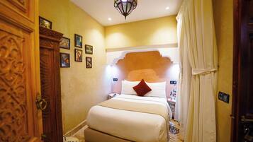 A hotel room with a large bed, a wooden wardrobe, and a decorative ceiling light.