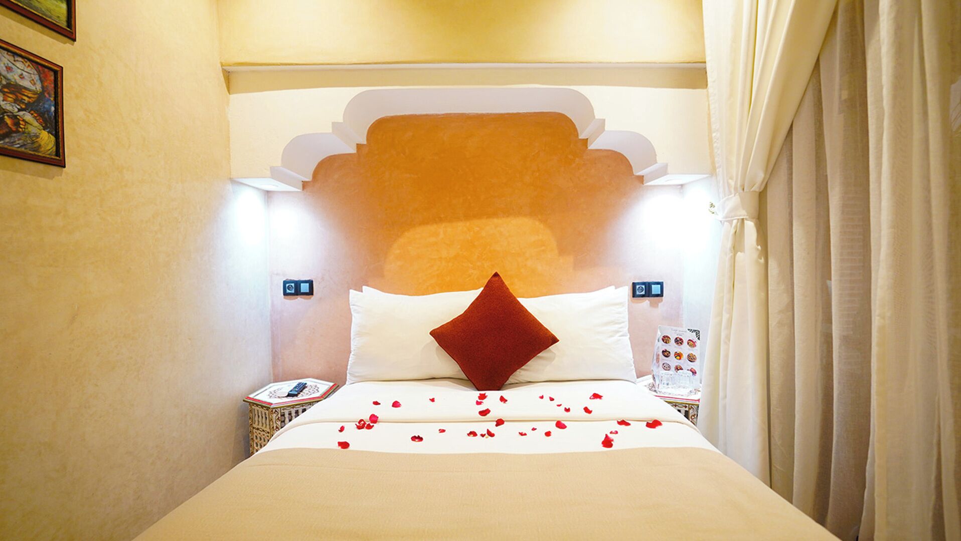 Una habitación de hotel con una cama grande, un cabecero decorativo y una mesita de noche con un teléfono.