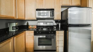A kitchen with wooden cabinets, a stainless steel stove, a microwave, and a refrigerator.