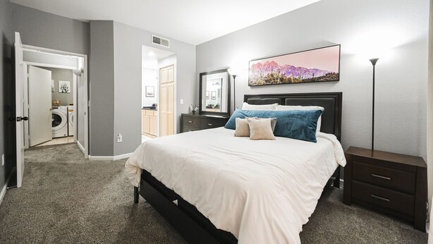 A bedroom with a bed, bedside tables, a nightstand, a dresser, and a wall-mounted TV.
