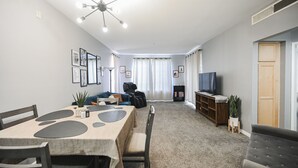 A modern living room with a dining area, a TV, and a sofa.