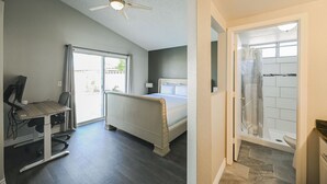 A bedroom with a bed, a desk with a computer, a ceiling fan, and a bathroom with a shower and toilet. - SVS: 3BD/2BA Residential Home | Quiet Neighborhood | Sleeps 6 (Las Vegas)