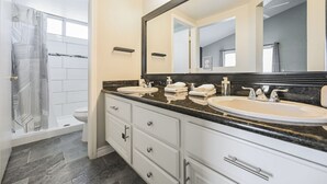 A modern bathroom with a walk-in shower, two sinks, a large mirror, and a vanity with drawers. - SVS: 3BD/2BA Residential Home | Quiet Neighborhood | Sleeps 6 (Las Vegas)