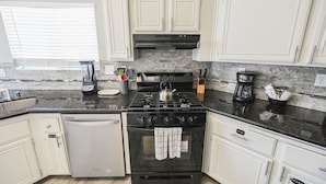 A modern kitchen with white cabinets, a black stove, and a dishwasher. - SVS: 3BD/2BA Residential Home | Quiet Neighborhood | Sleeps 6 (Las Vegas)