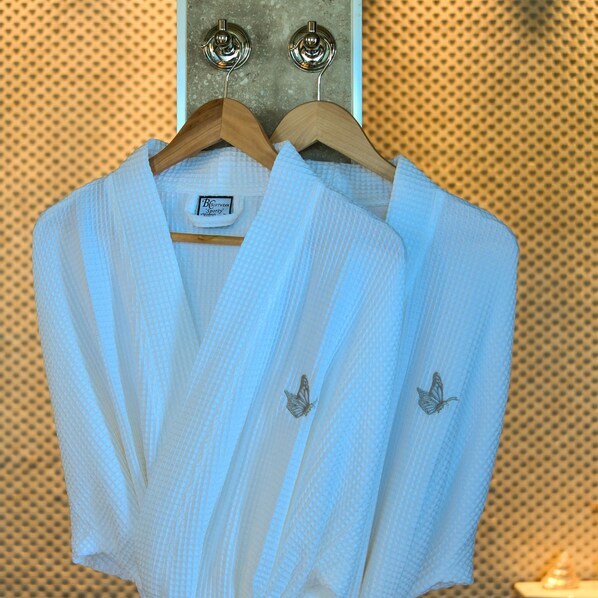 A rack with two light blue shirts, each with a small butterfly embroidery on the left side. - Villa Papillon (Jolly Harbour)
