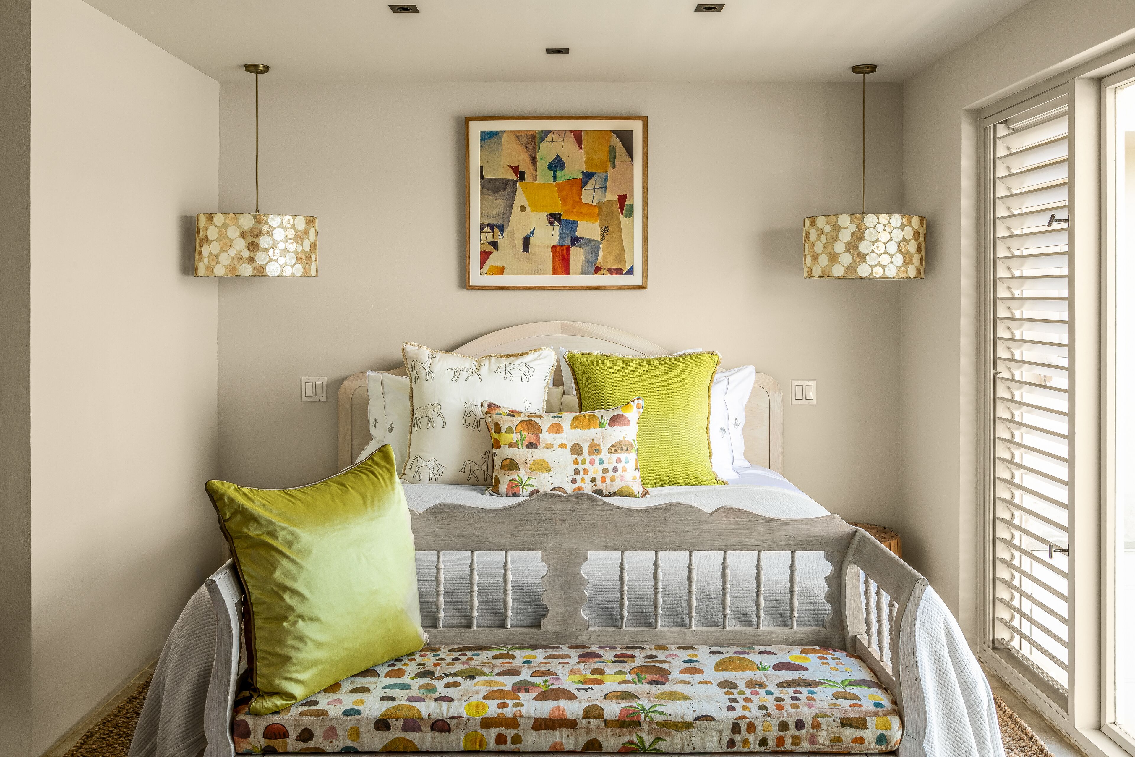 A cozy bedroom with a bed, pillows, and a wall-mounted abstract painting.