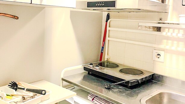 A compact kitchen with white cabinets, a stainless steel sink, and a built-in stove. - A Great Ramblas and Sea (Barcelona)