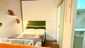 A small, compact room with a bed, a wardrobe, and a small table. - A Great Ramblas and Sea (Barcelona)