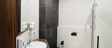 A modern bathroom with a marble sink, a toilet, and a glass shower enclosure.