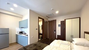 Une chambre d’hôtel avec un lit, une petite kitchenette et une salle de bain.