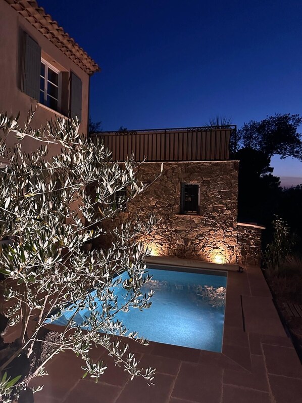 A stone building with a pool, surrounded by olive trees.