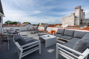 Um terraço no telhado com mobiliário externo, incluindo um sofá, cadeiras e uma mesa.
