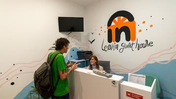 A reception desk with a logo for 'Levin Guest House' and a sign indicating 'No Smoking' and 'No Pets'.