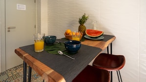 Una mesa de desayuno con tazones, vasos, una piña y una tajada de sandía.