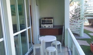 A balcony with a table and chairs, a toaster, and a spiral staircase in the background. - Morada da Praia (Bombinhas)