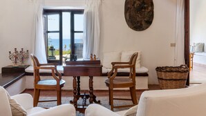 A room with a view of the sea, a wooden table, two chairs, a sofa, and a wall-mounted painting. - Villa La Fenice by Wonderful Italy (Castellammare del Golfo)