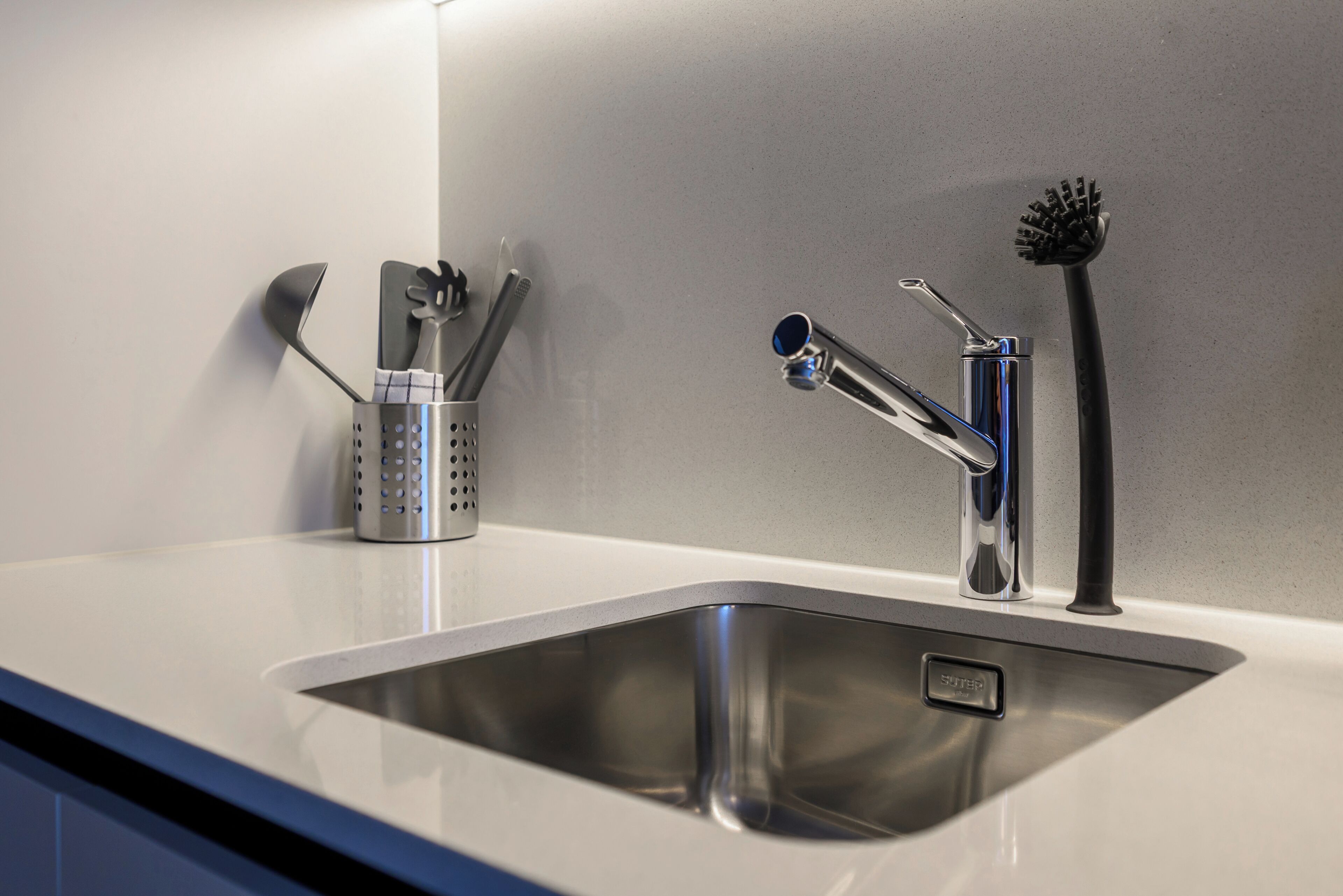 A modern kitchen sink with a stainless steel faucet and a soap dispenser.