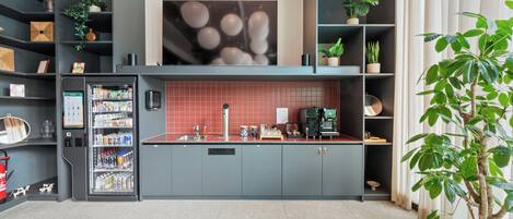 A modern kitchen with grey cabinets, a red backsplash, and a built-in coffee machine.