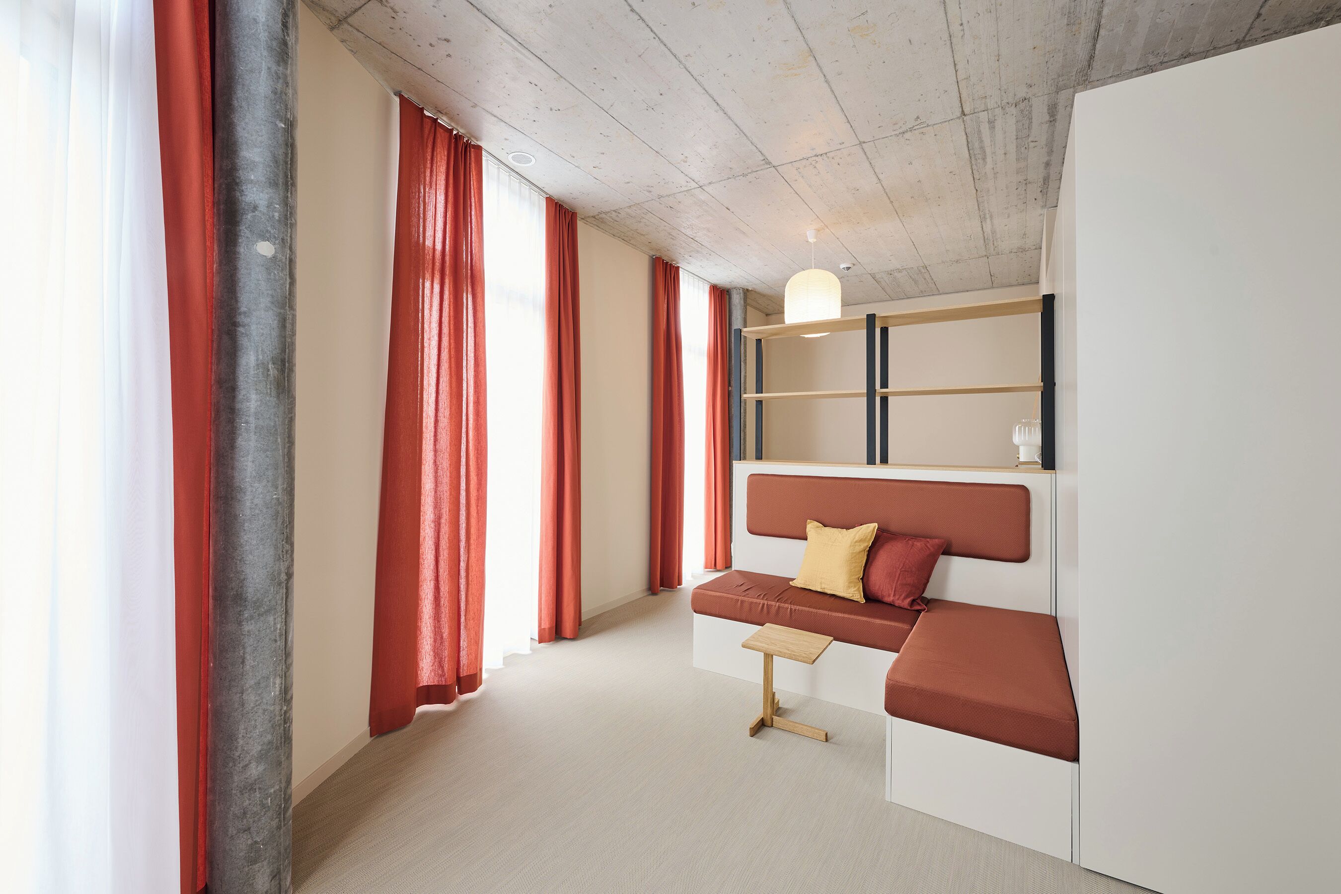 A modern room with a sofa, a small table, and a hanging light fixture.