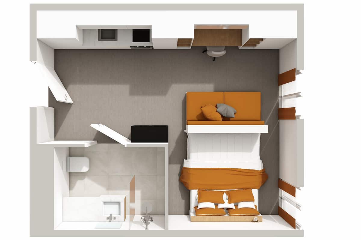 A compact studio apartment layout with a kitchenette, a small bathroom, a seating area with a sofa and cushions, and a bed.