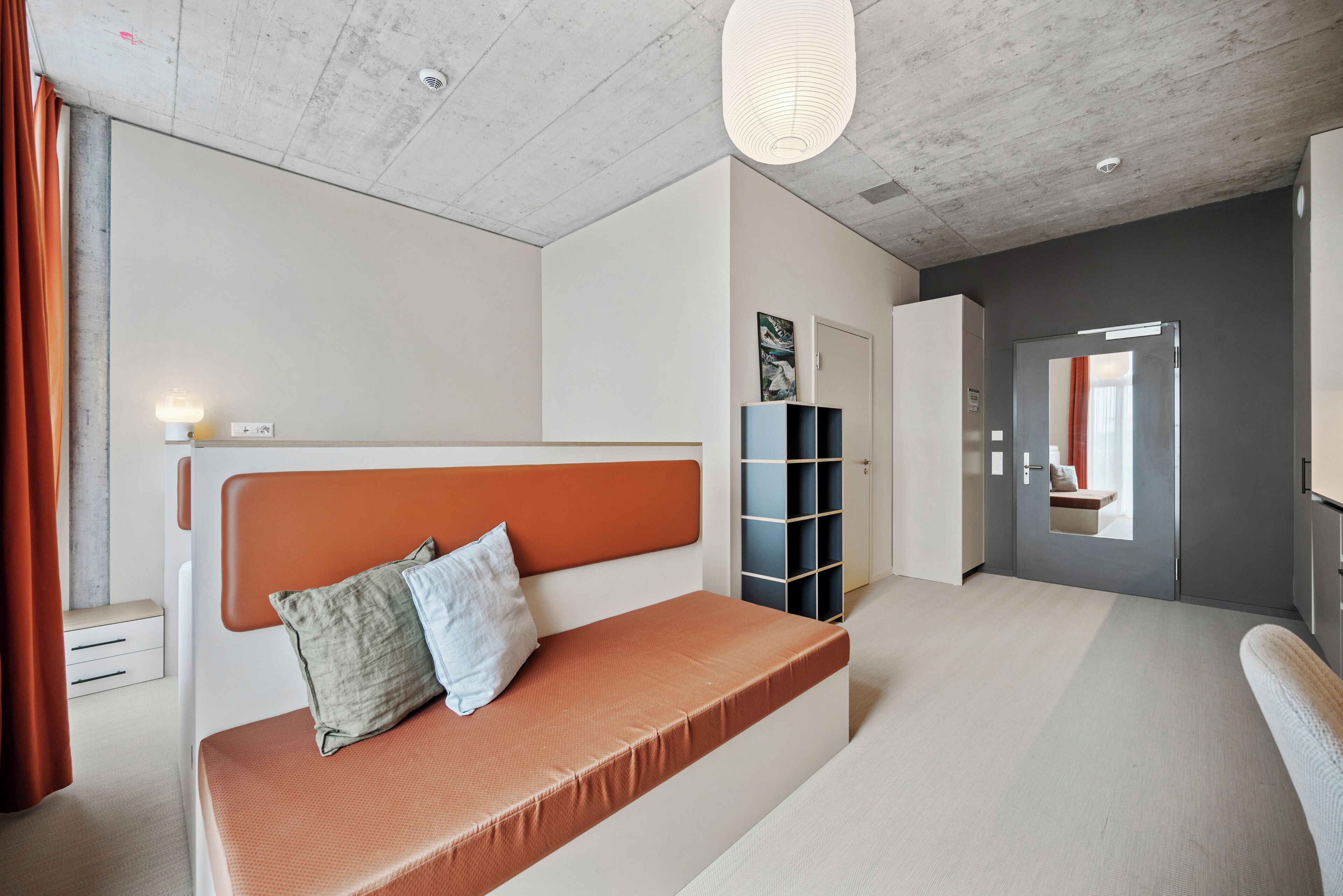 Ein modernes Schlafzimmer mit einem großen Bett, einem Nachttisch, einem Kleiderschrank und einer Tür zu einem anderen Raum.