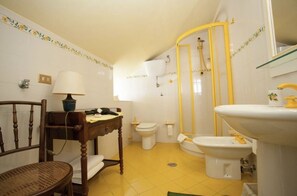 Une salle de bain équipée de toilettes, d’un bidet, d’un lavabo et d’une chaise.