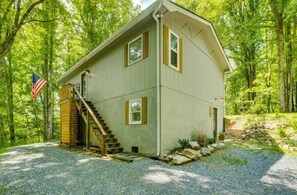 A single-story house with a wooden staircase leading to the entrance, surrounded by trees. - Deer Run Cottage (Laurel Bloomery)