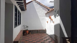 Un patio estrecho con suelo de baldosas, paredes blancas y techo de tejas.