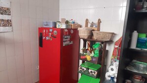 Una cocina compacta con un refrigerador rojo, una estantería con cestas y diversos utensilios de cocina.