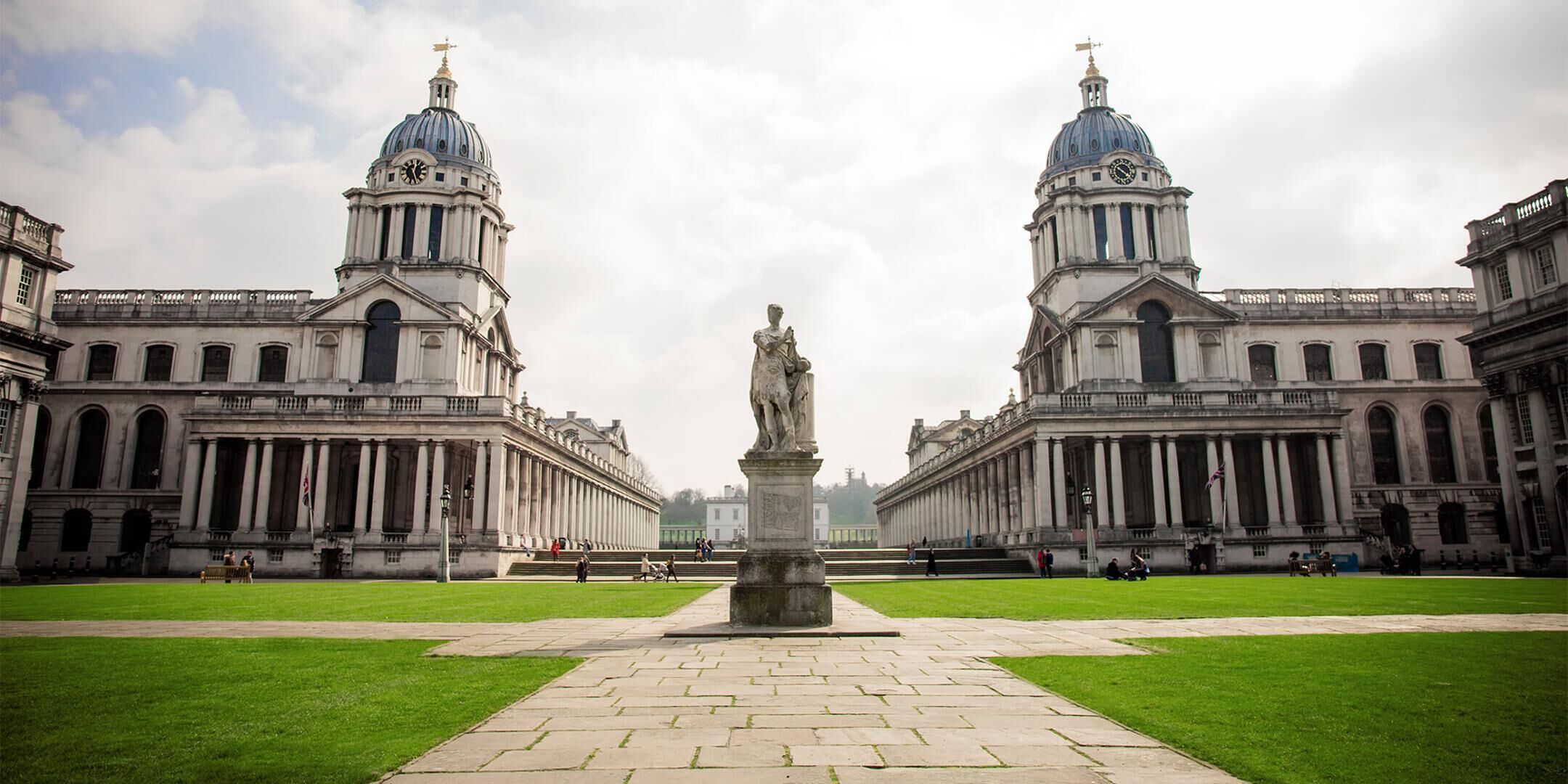 A symmetrical building with two large domes and a central statue.