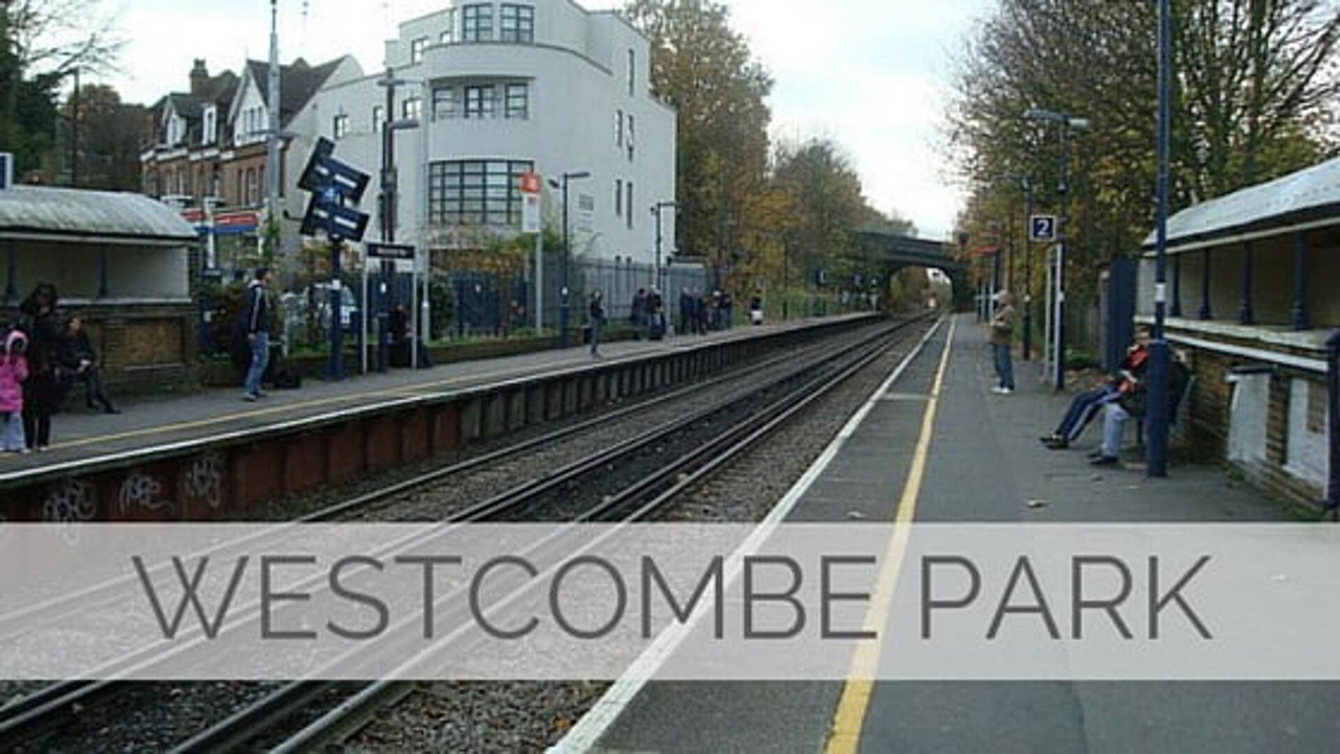 Et togstationsperron med en moderne bygning i baggrunden.