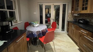A compact kitchen with a dining table, red chairs, and wooden cabinets.