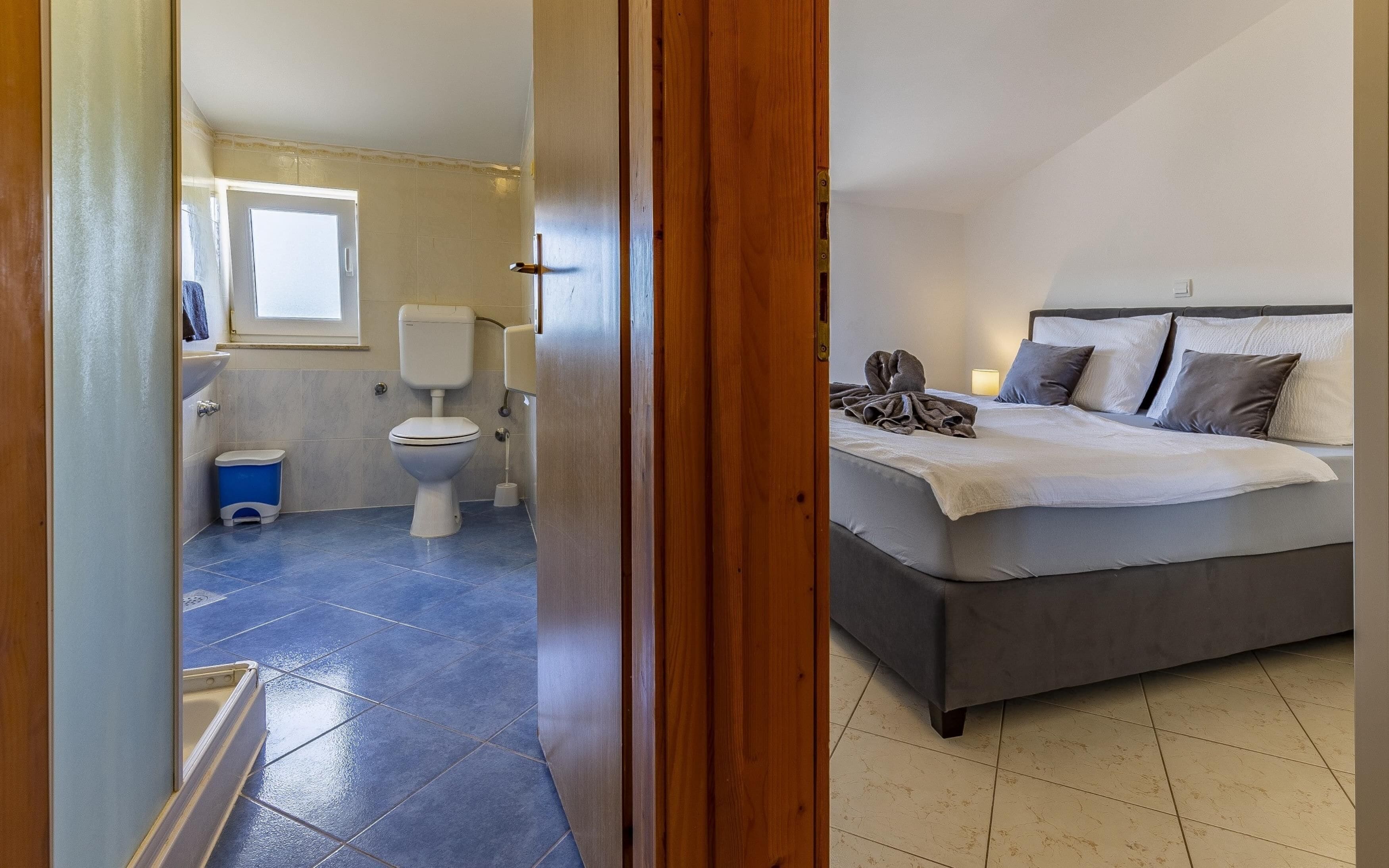 A bedroom with a bed, a bathroom with a toilet, and a window.